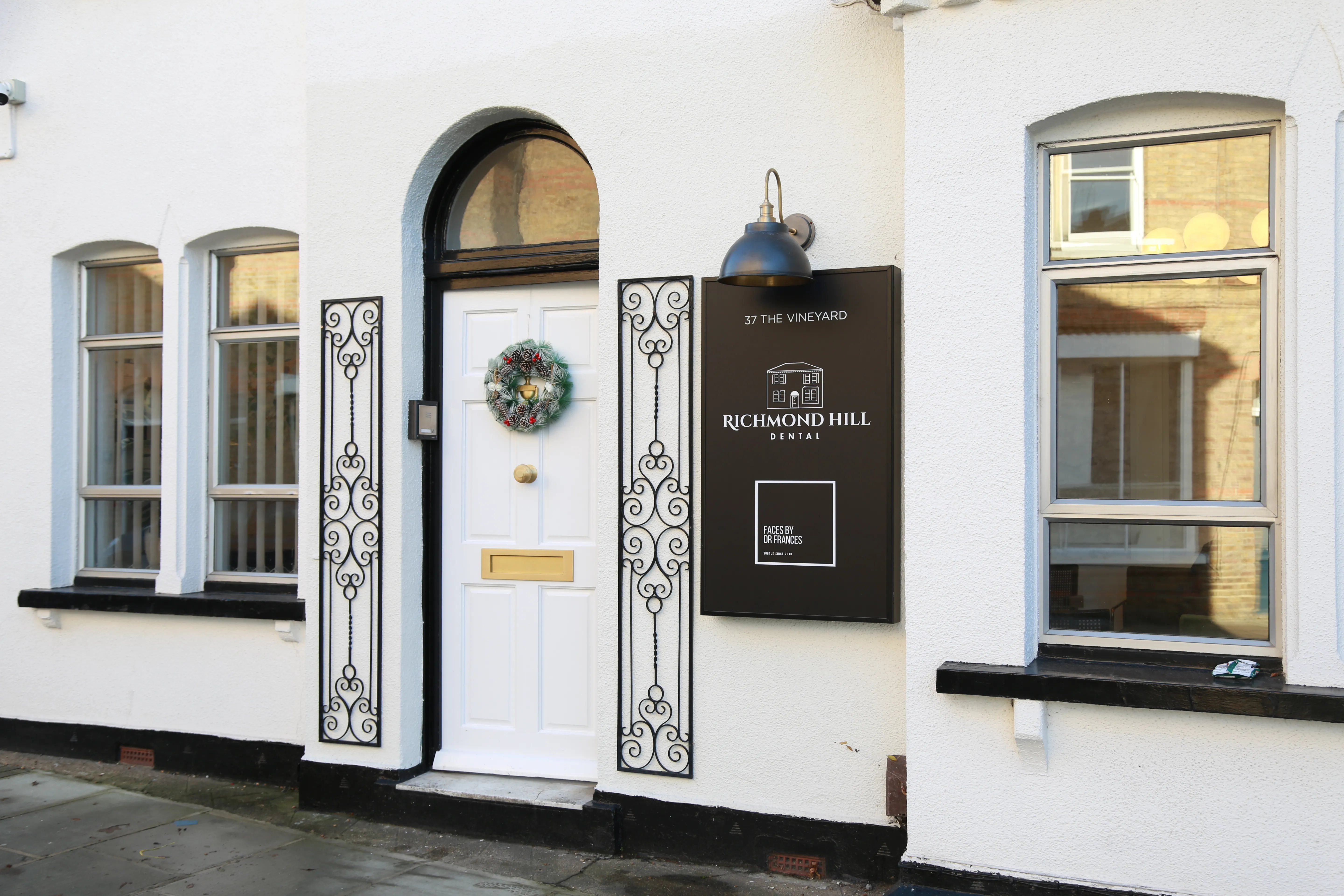 White building entrance with a wreath on the door and Richmond Hill Dental sign outside.