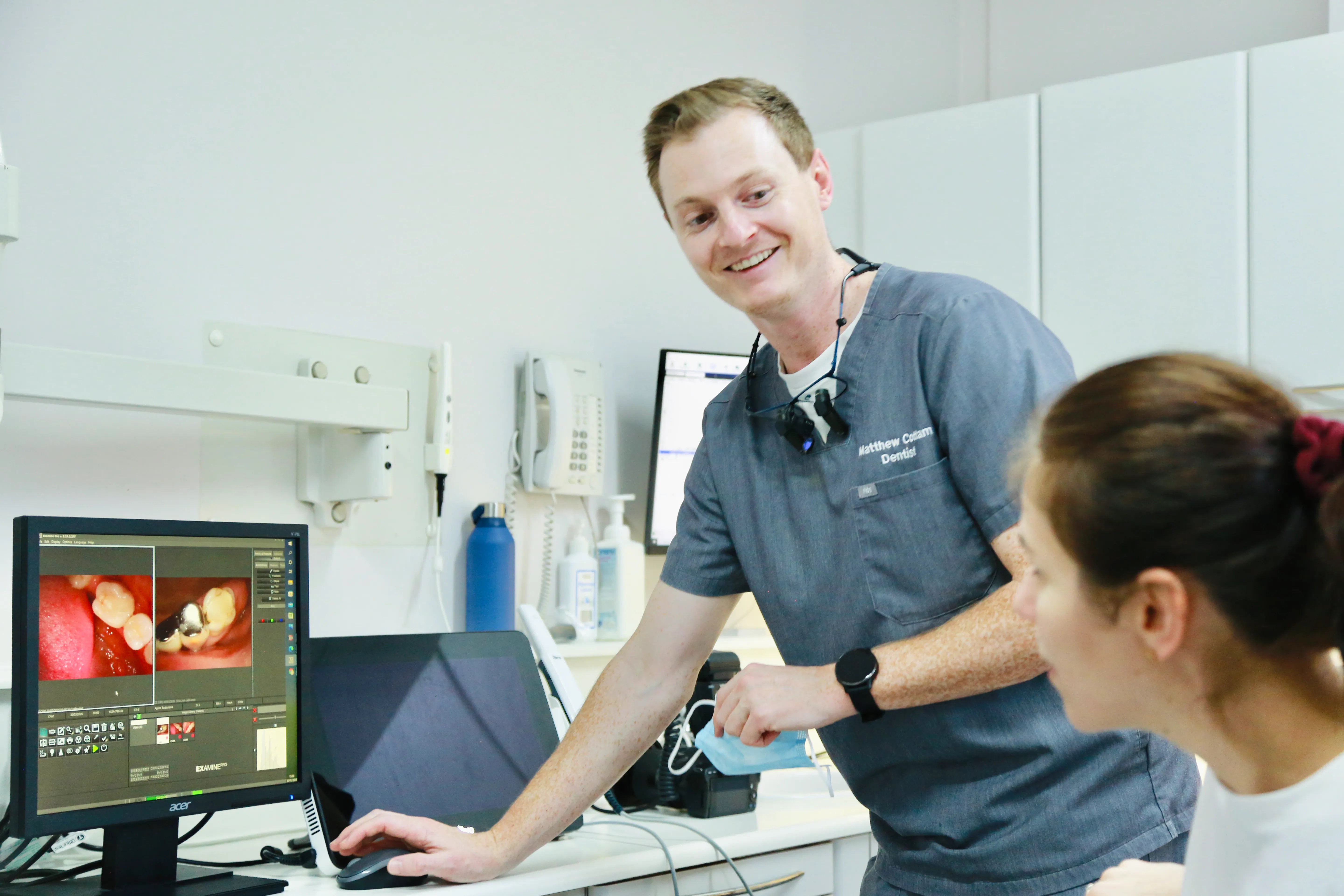 Dentist showing dental images on a computer screen to a patient in a clinic.