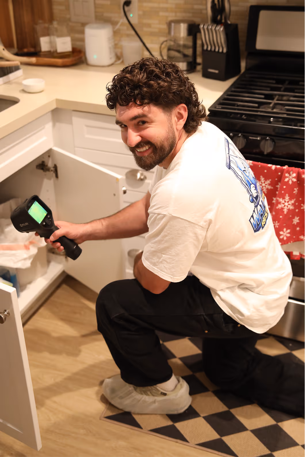 Water Gone Restoration technician inspecting under a sink with a thermal camera