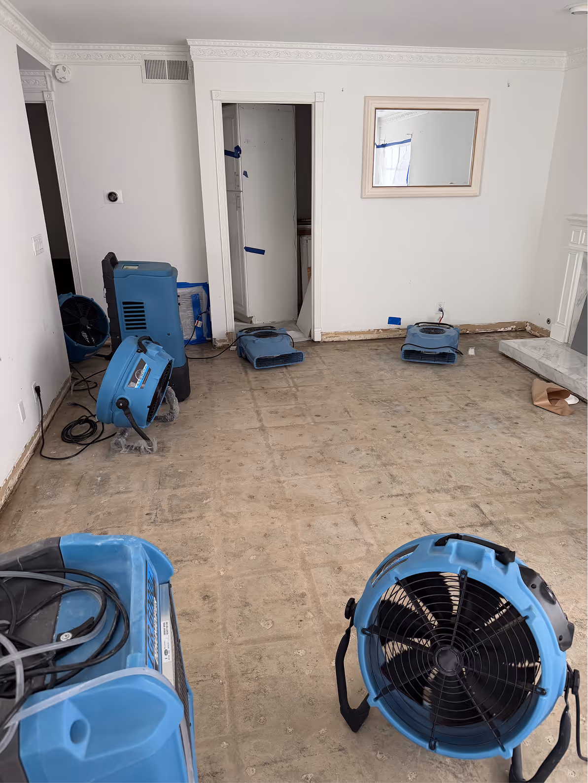 Air movers drying an exposed subfloor after flooring removal