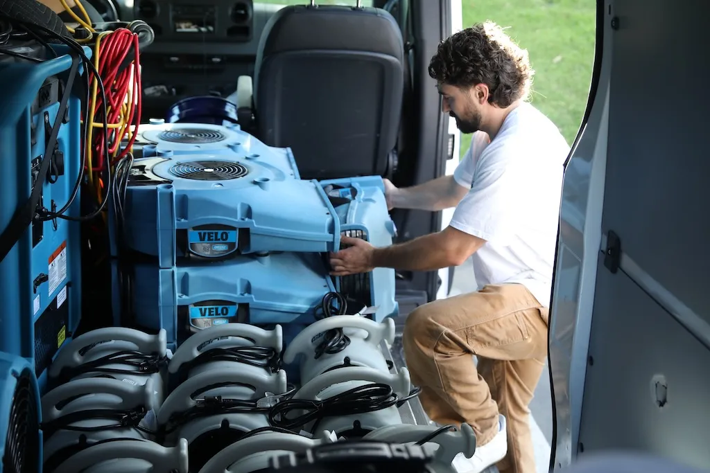 Technician unloading air movers from the Water Gone Restoration service van