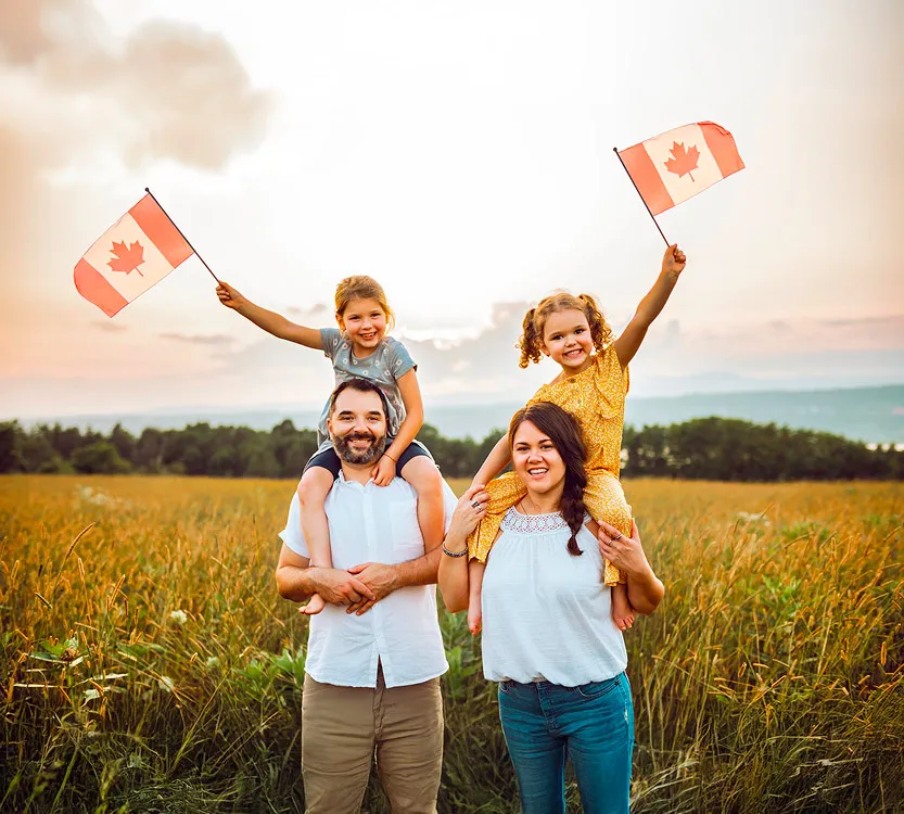 A family waving canadian flags while standing in a field.