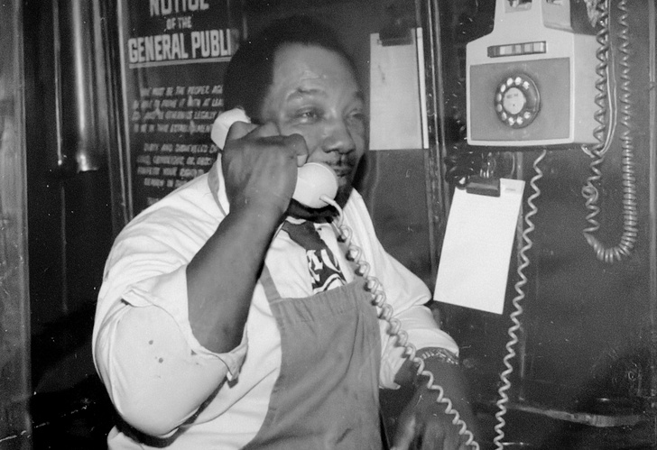 Hercules, Butch McGuire's legendary chili cook, answering the phone behind the bar
