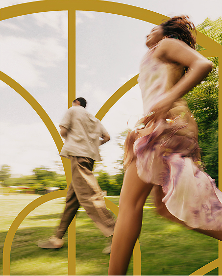 Blurred image of a woman and man running outdoors on green grass with trees and cloudy sky.