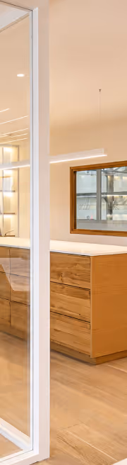 Cuisine moderne avec des armoires en bois clair et un miroir encadré sur le mur beige.