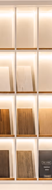 Wood samples displayed in a vertical lit shelving unit for flooring or furniture choices.