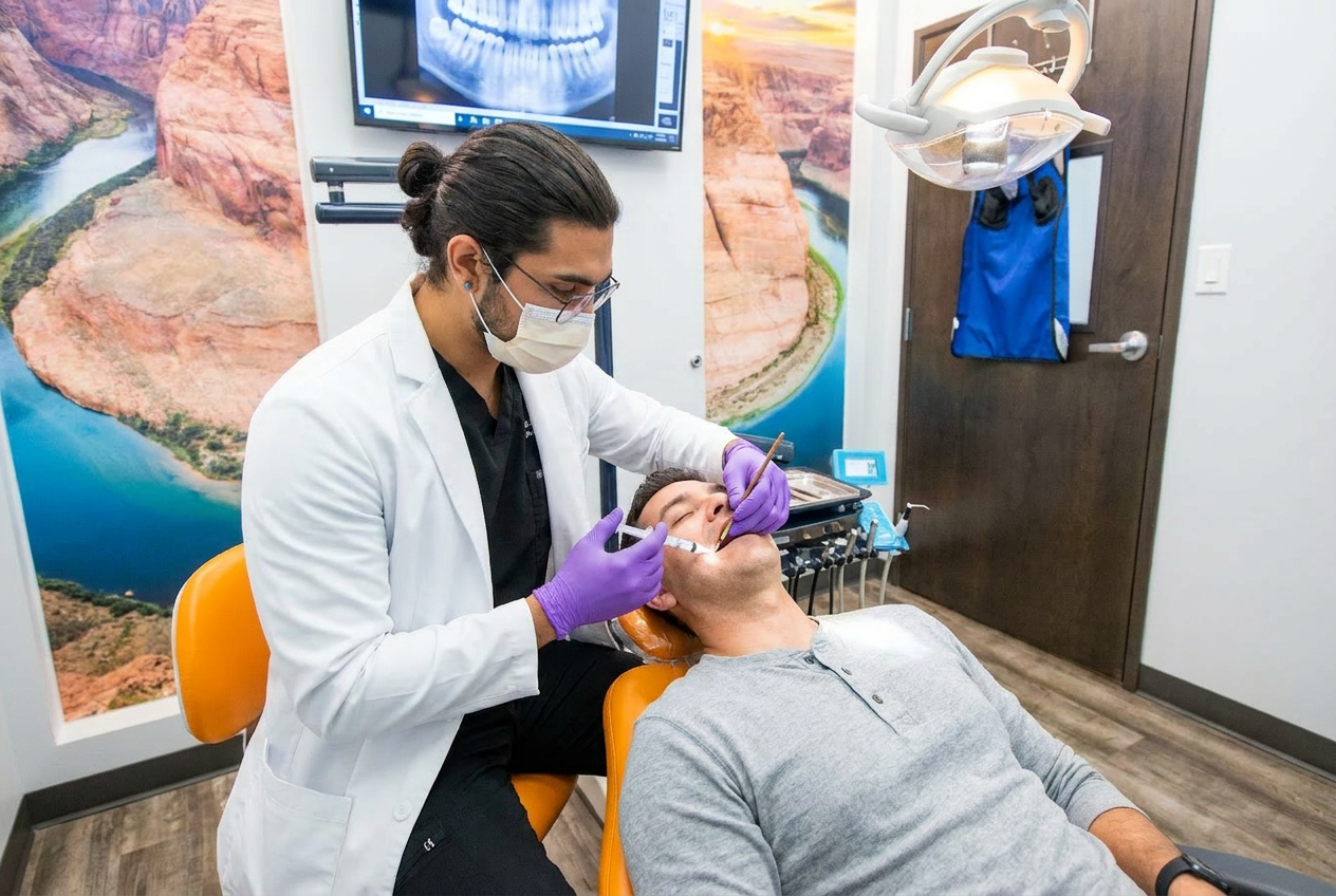 Dr. Karnik Shah placing a dental filling on a male patient with a full mouth x-ray visible on screen at Comfydent Smiles in Bee Cave, TX.