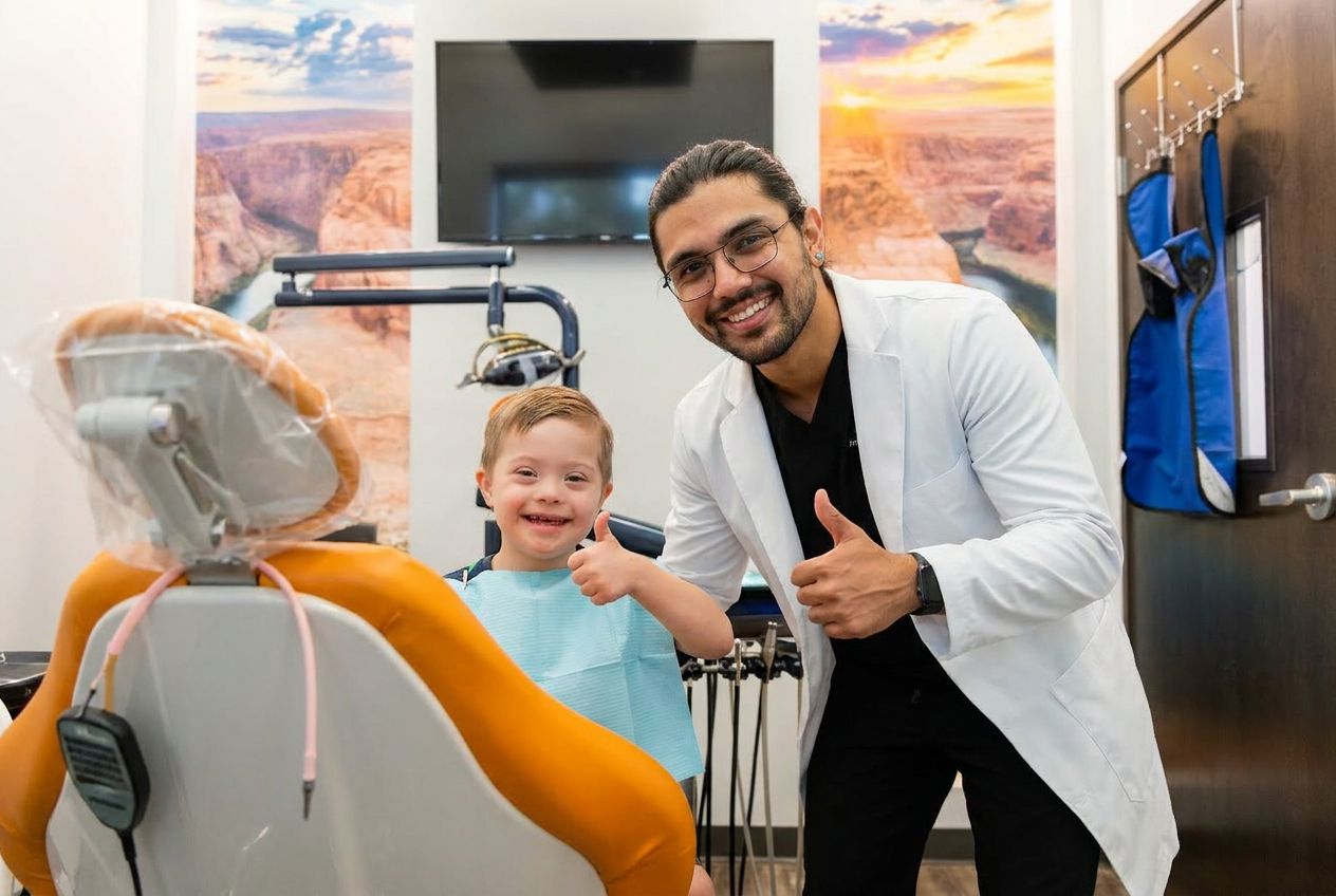 Dr. Karnik Shah giving a thumbs up next to a smiling young boy with Down syndrome seated in the dental chair at Comfydent Smiles in Bee Cave, TX.