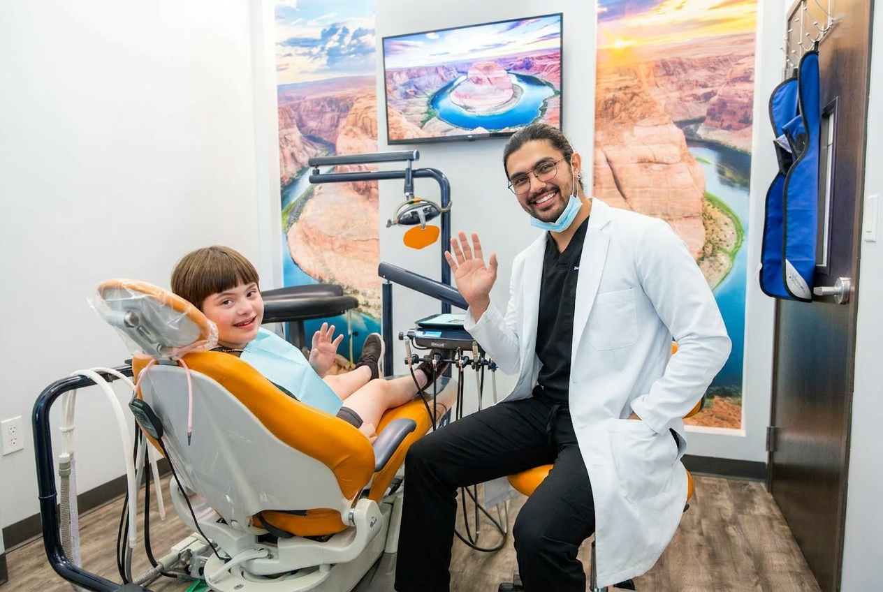Dr. Karnik Shah waving alongside a young boy with Down syndrome seated in the treatment chair at Comfydent Smiles in Bee Cave, TX.