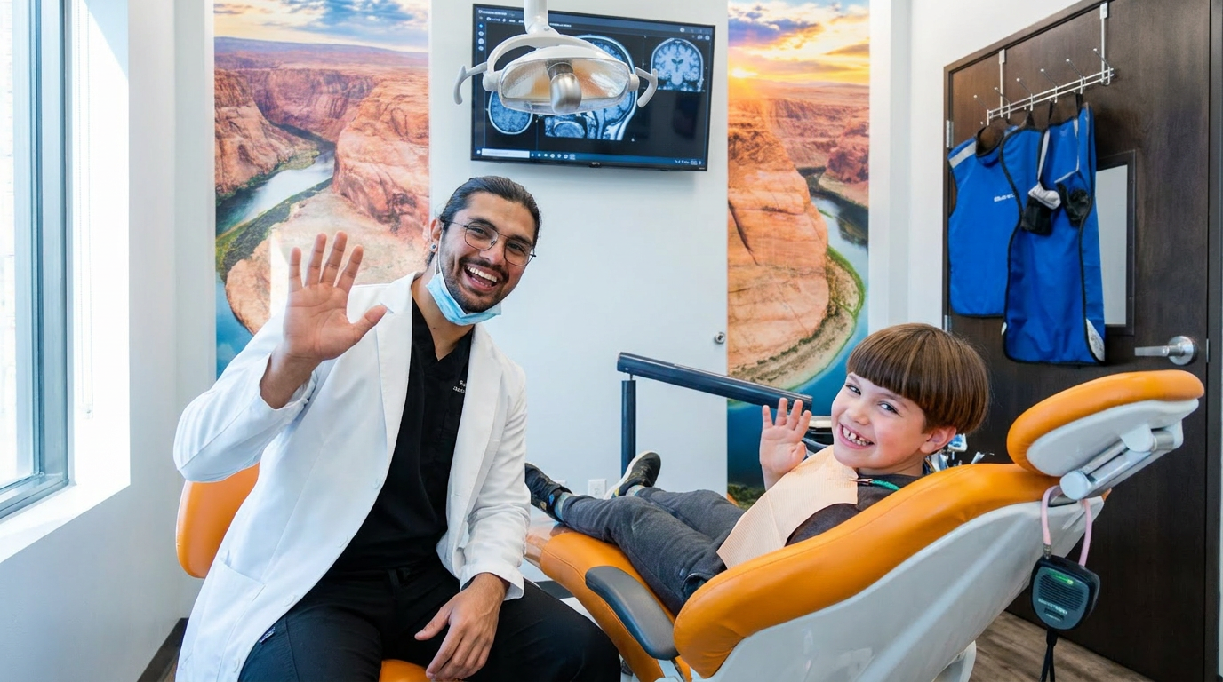 Dr. Karnik Shah and a smiling young boy both waving at the camera during a children's dental visit at Comfydent Smiles in Bee Cave, TX.