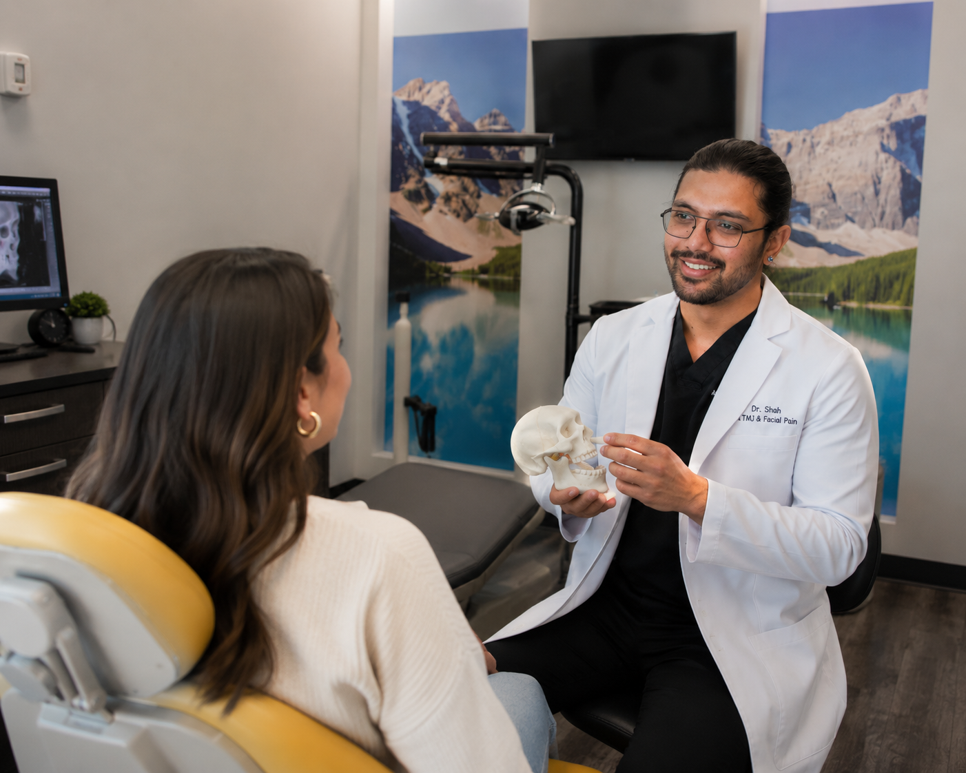 Dr. Karnik Shah holding a jaw anatomy model and consulting with a female patient about TMJ treatment at Comfydent Smiles in Bee Cave, TX.