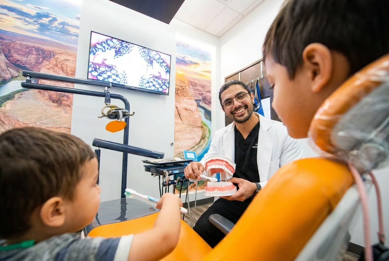 Pediatric dentist teaching two children proper brushing techniques using a dental model in a friendly exam room