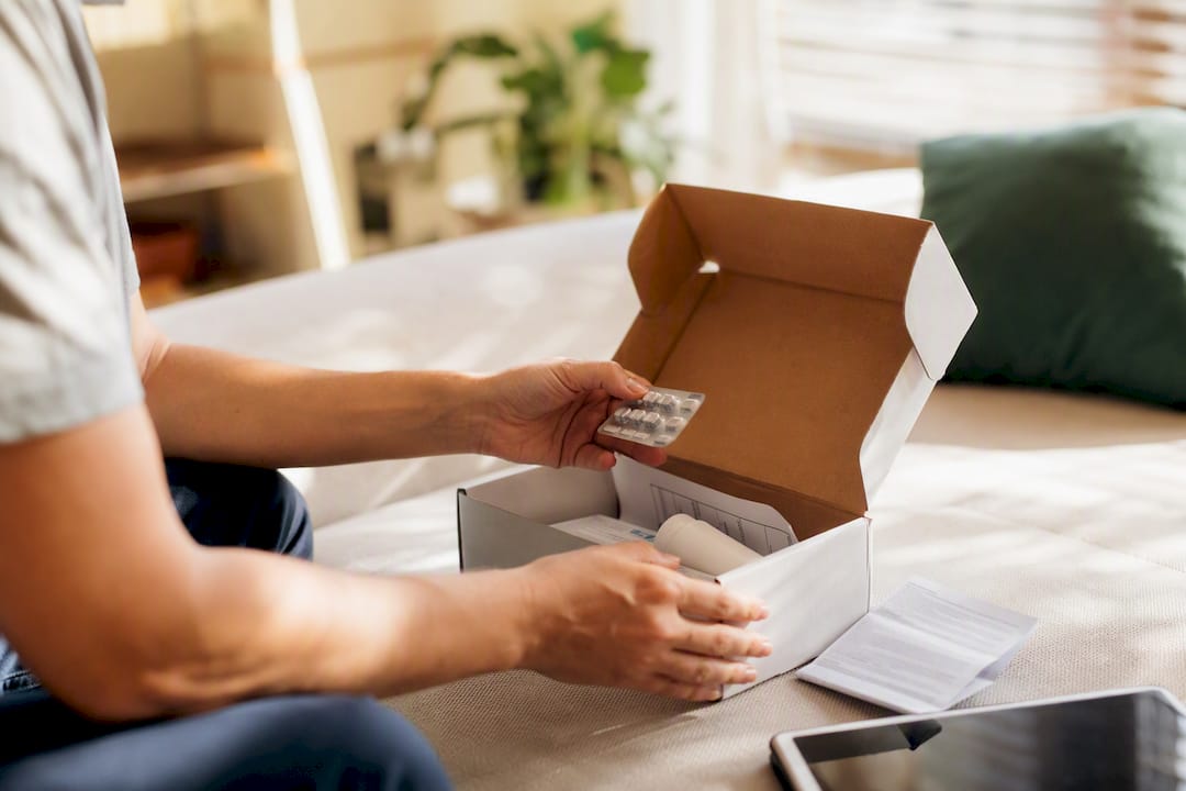 Hands holding prescription medication from delivery package
