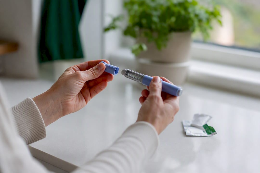 Hands removing cap of injection pen