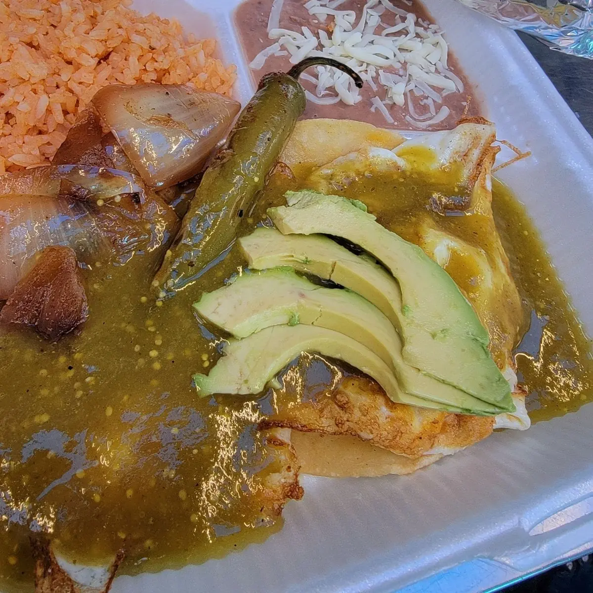 Authentic Mexican huevos rancheros breakfast served with fried eggs, warm salsa, and refried beans at a local restaurant in Bakersfield, CA.