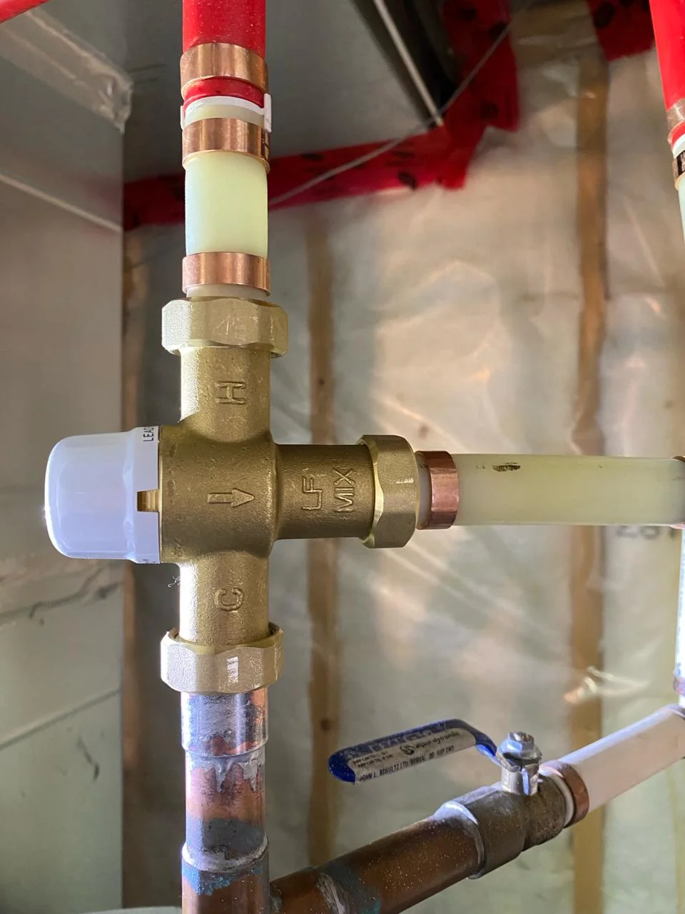 Close up of a thermostatic mixing valve showing hot cold and mix connections - Hive 5 Plumbing Vaughan
