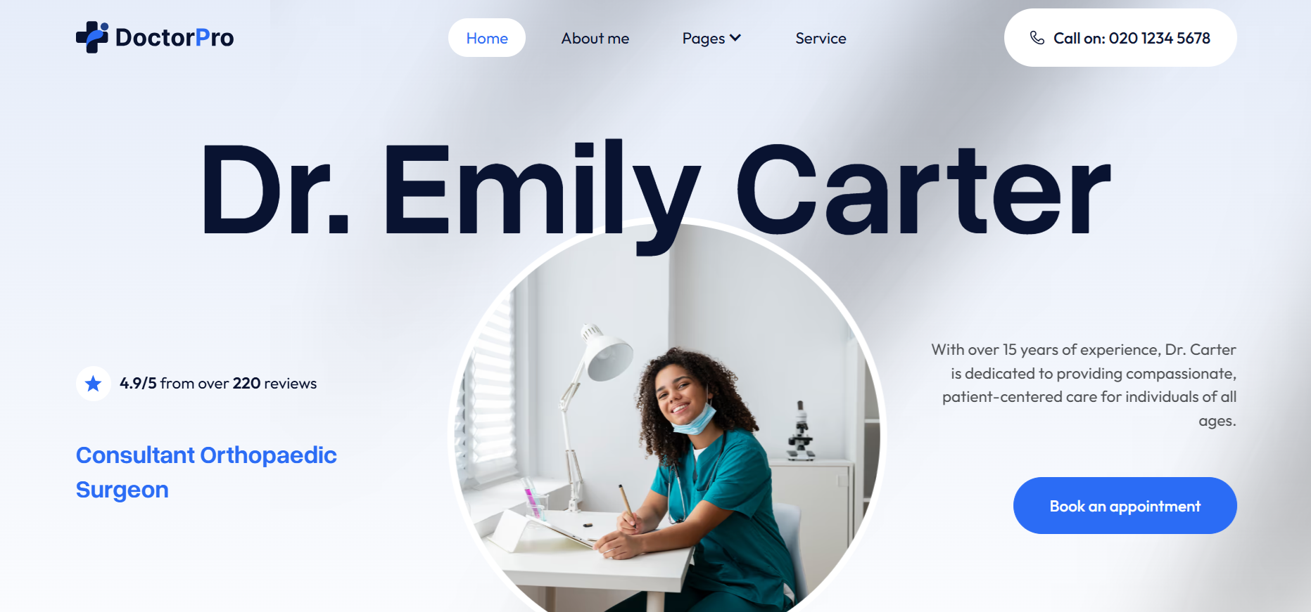 Smiling female doctor in green scrubs sitting at desk with lamp and microscope behind her.