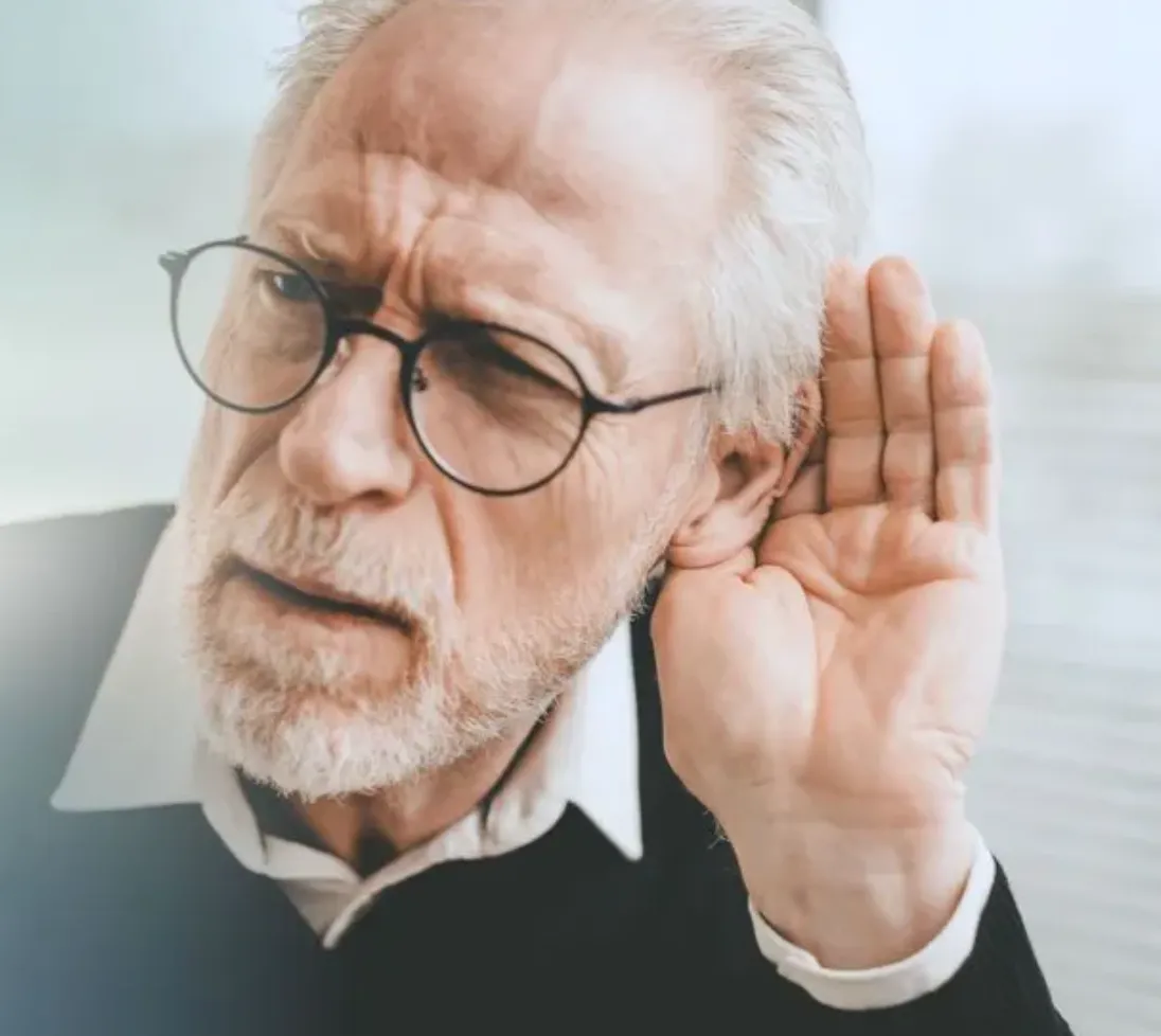 Older man with glasses cupping hand to ear as if trying to hear better.
