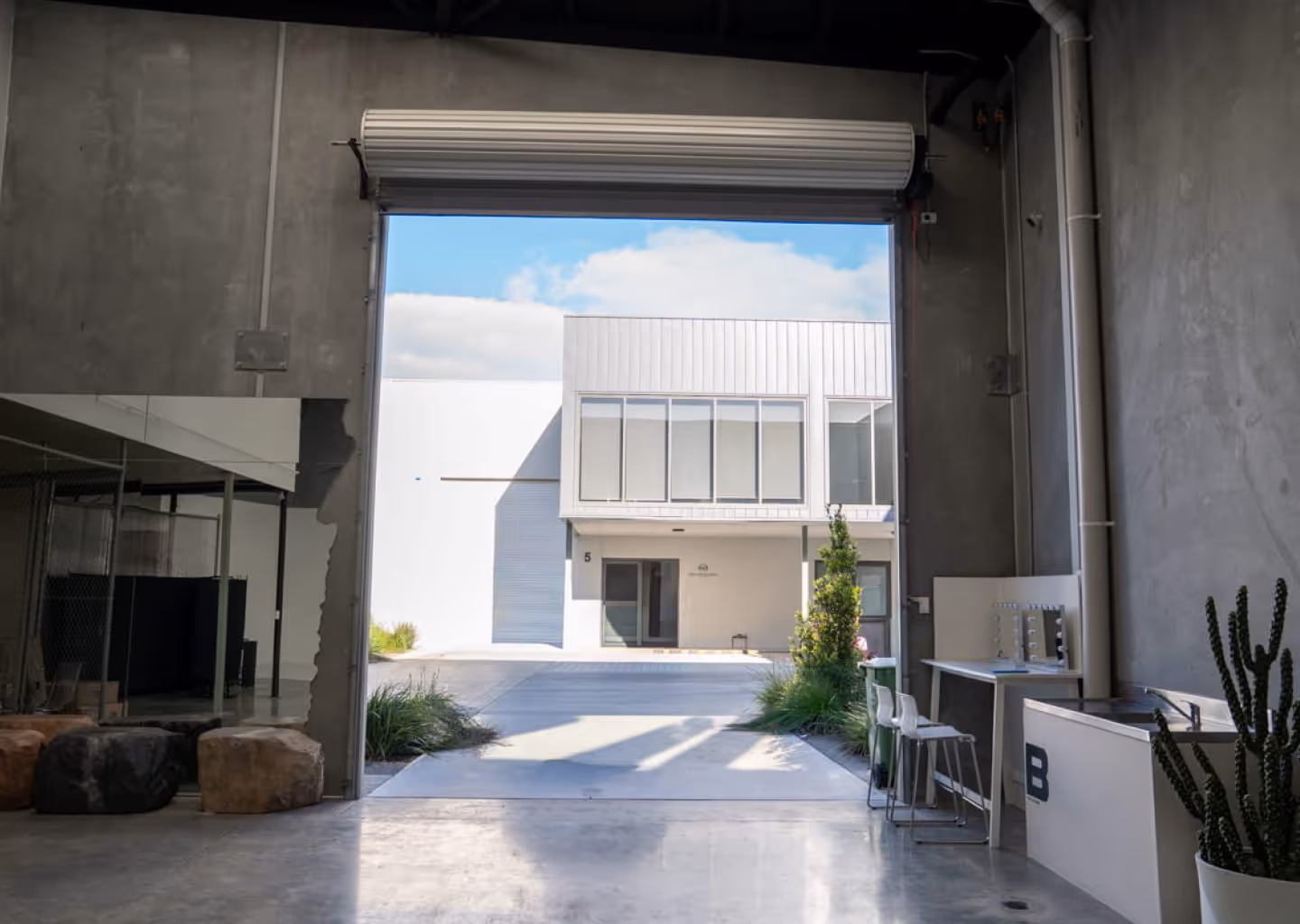 View from inside BLANK Studio opening toward a modern two-story building with large windows and driveway.