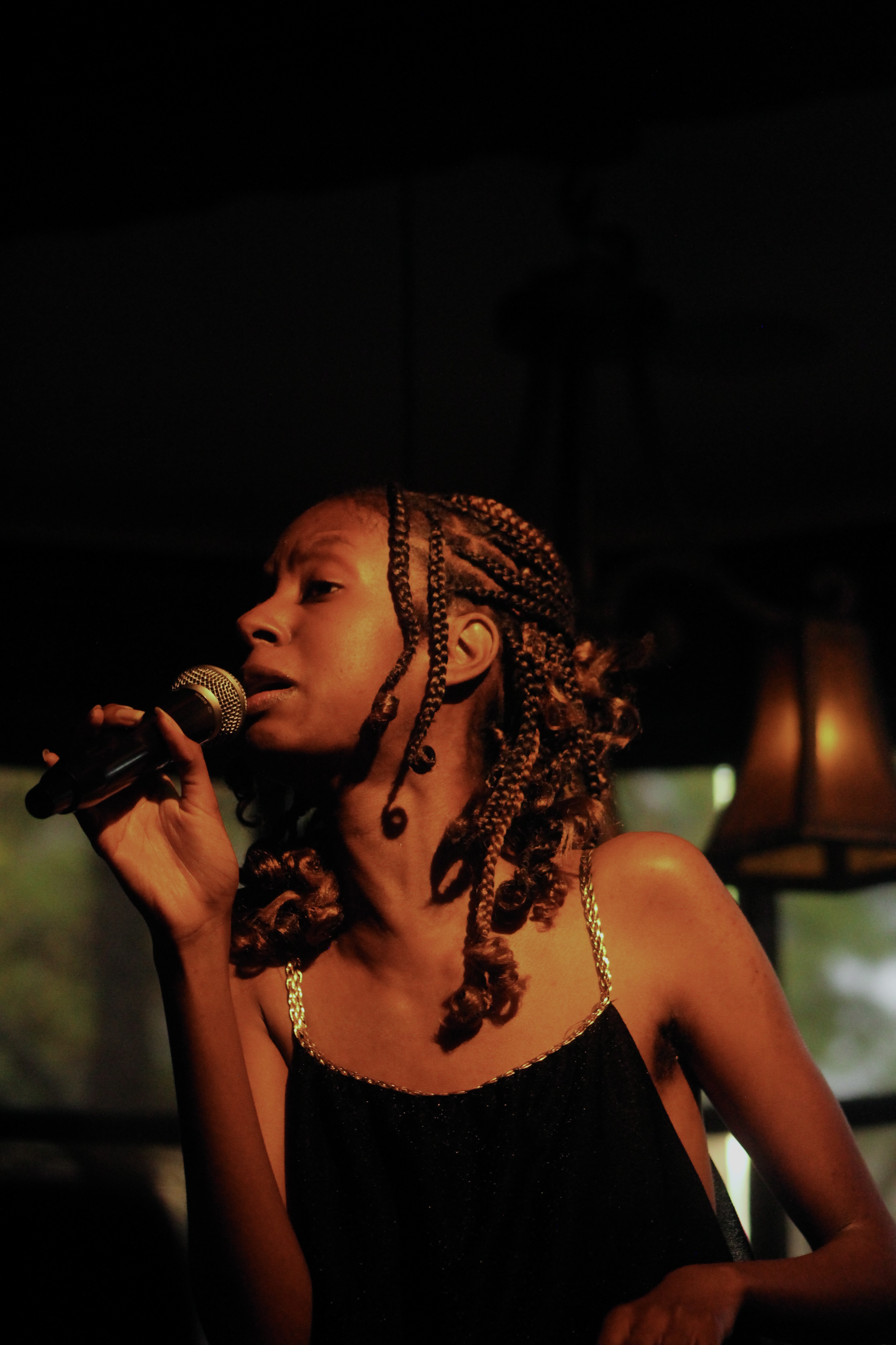 Afiya Userkaf sings jazz as the indoor lighting lights her as though the sun was upon her skin.