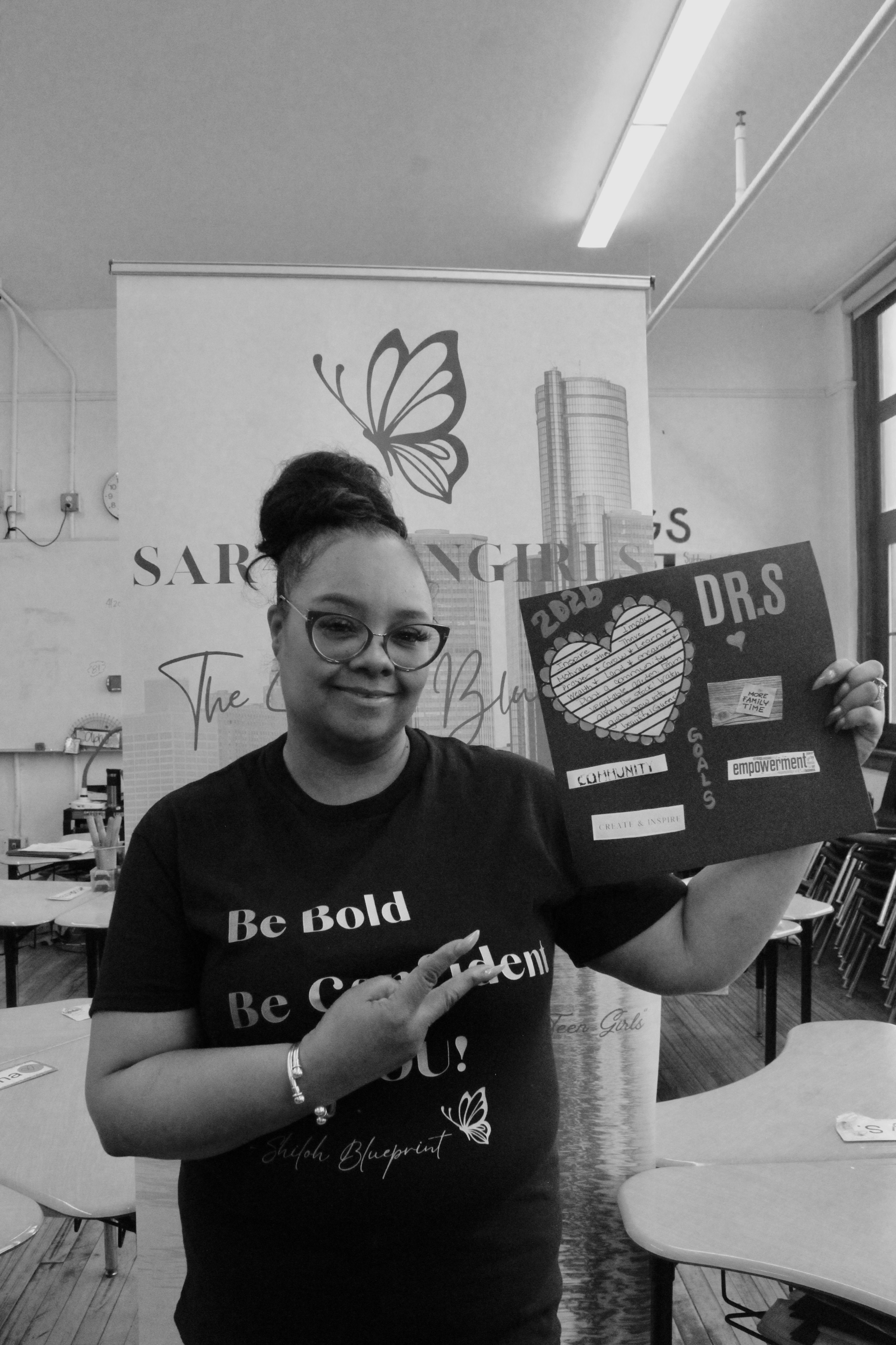 Dr. Shalonda humbly poses with her vision board in this black and white image.