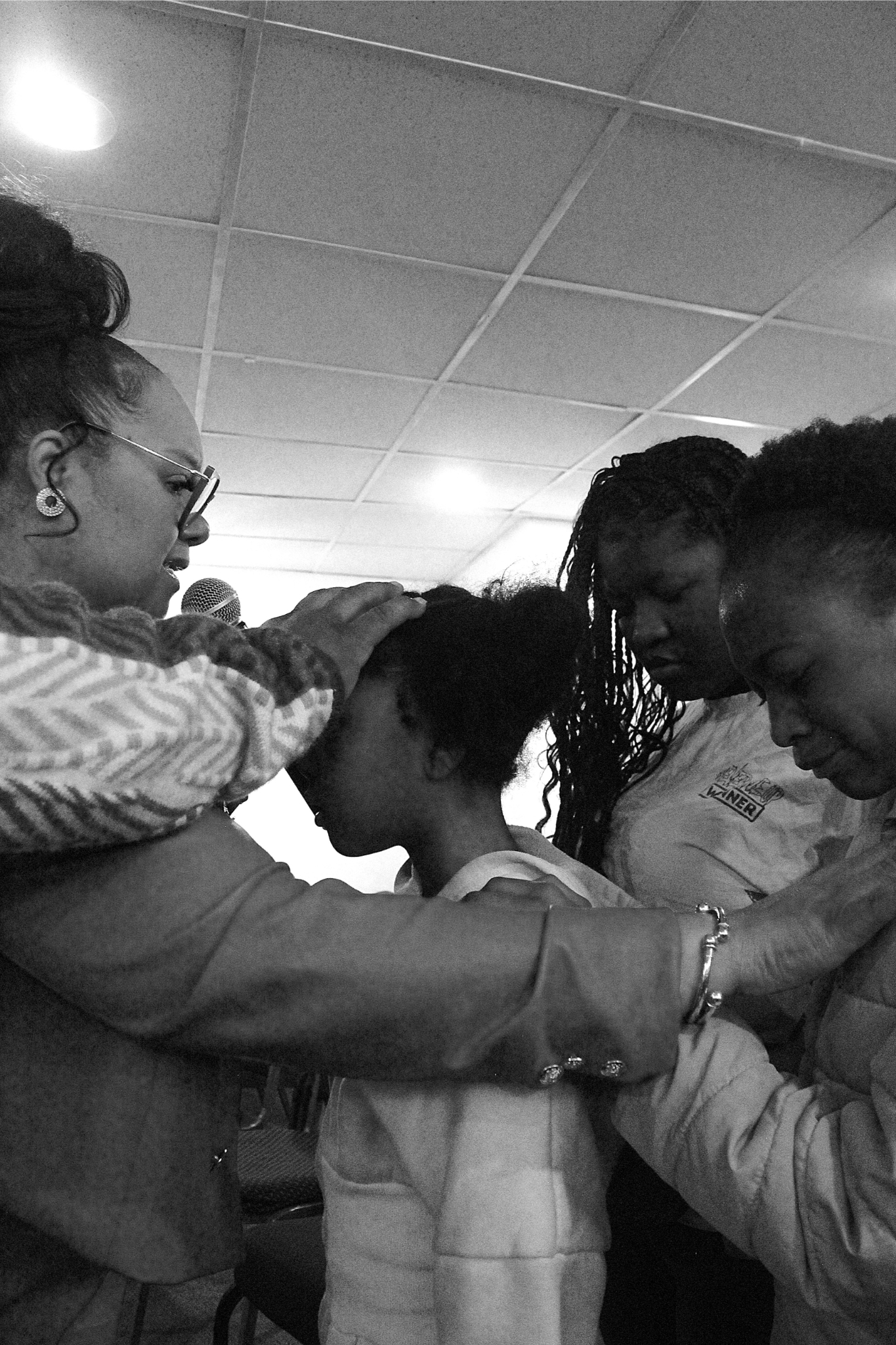 In this black and white image, Co-Pastor’s and Pastor’s arms intertwine as they lay their hands on the foreheads of babes.