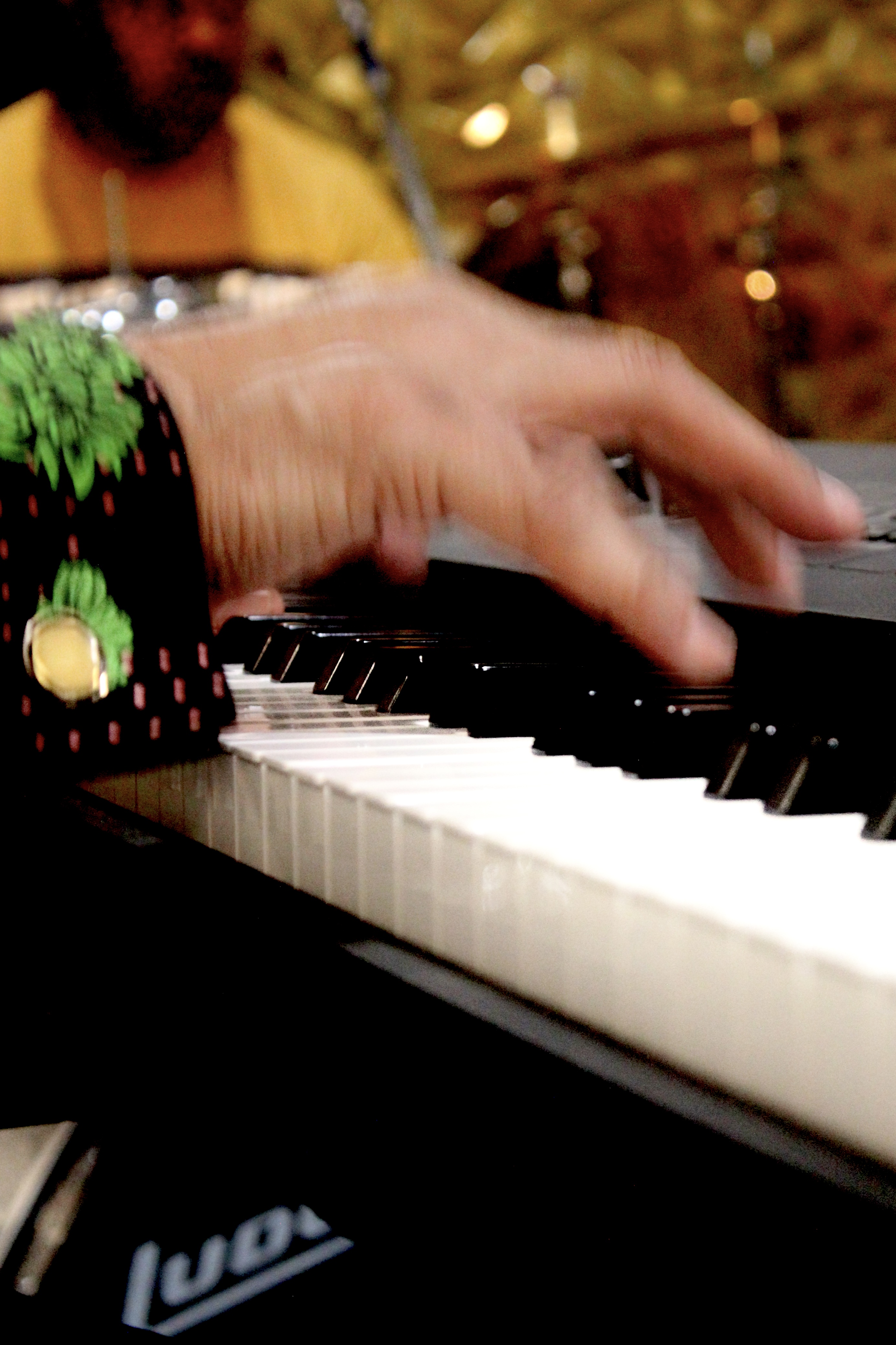Captured in motion, the hands of a light-skinned male rise above keyboard keys.