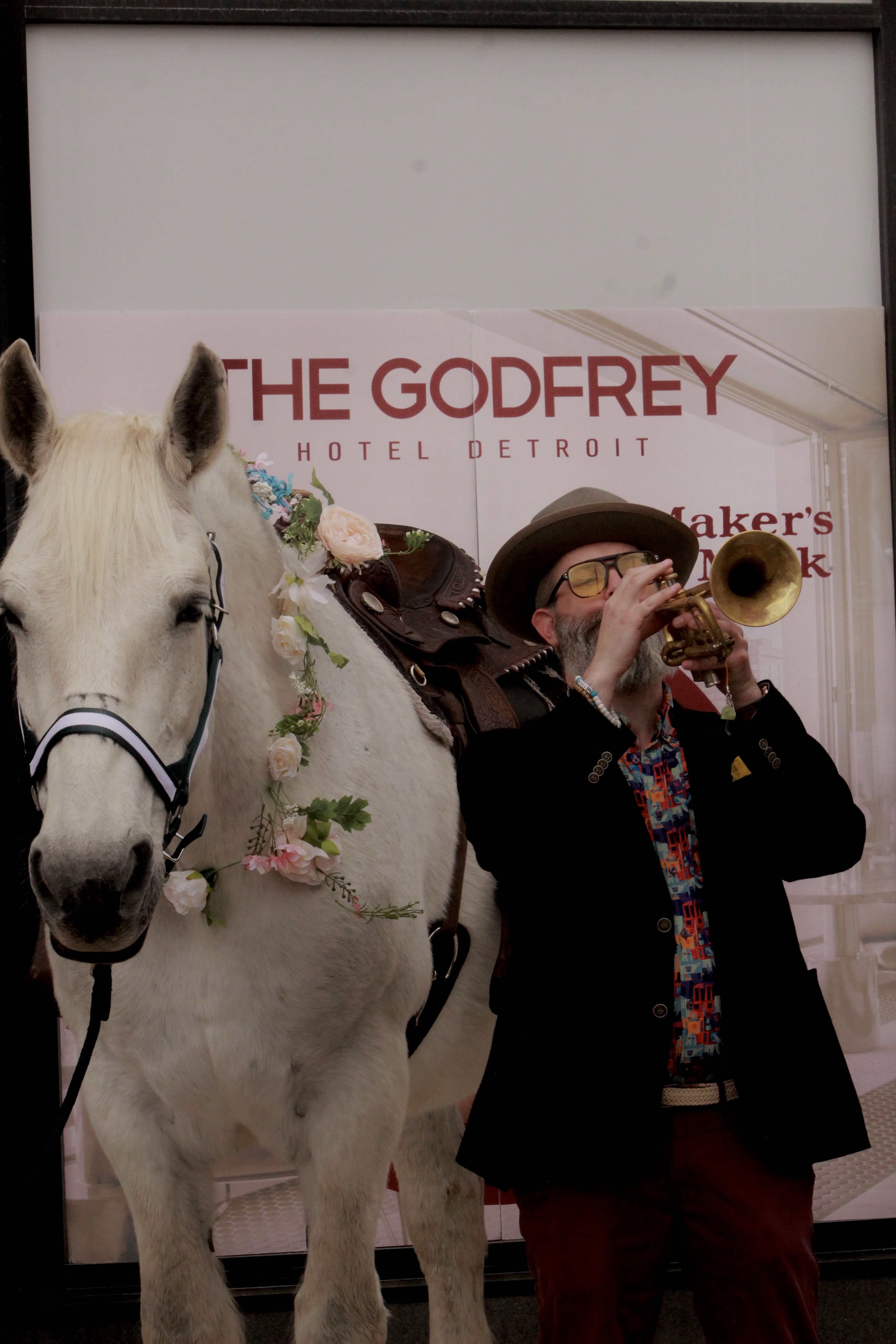 In front of the Godfrey Hotel Detroit, RIch (right) stands next to Babe-a grey, female Percheron (horse)-(left) as he plays the trumpet