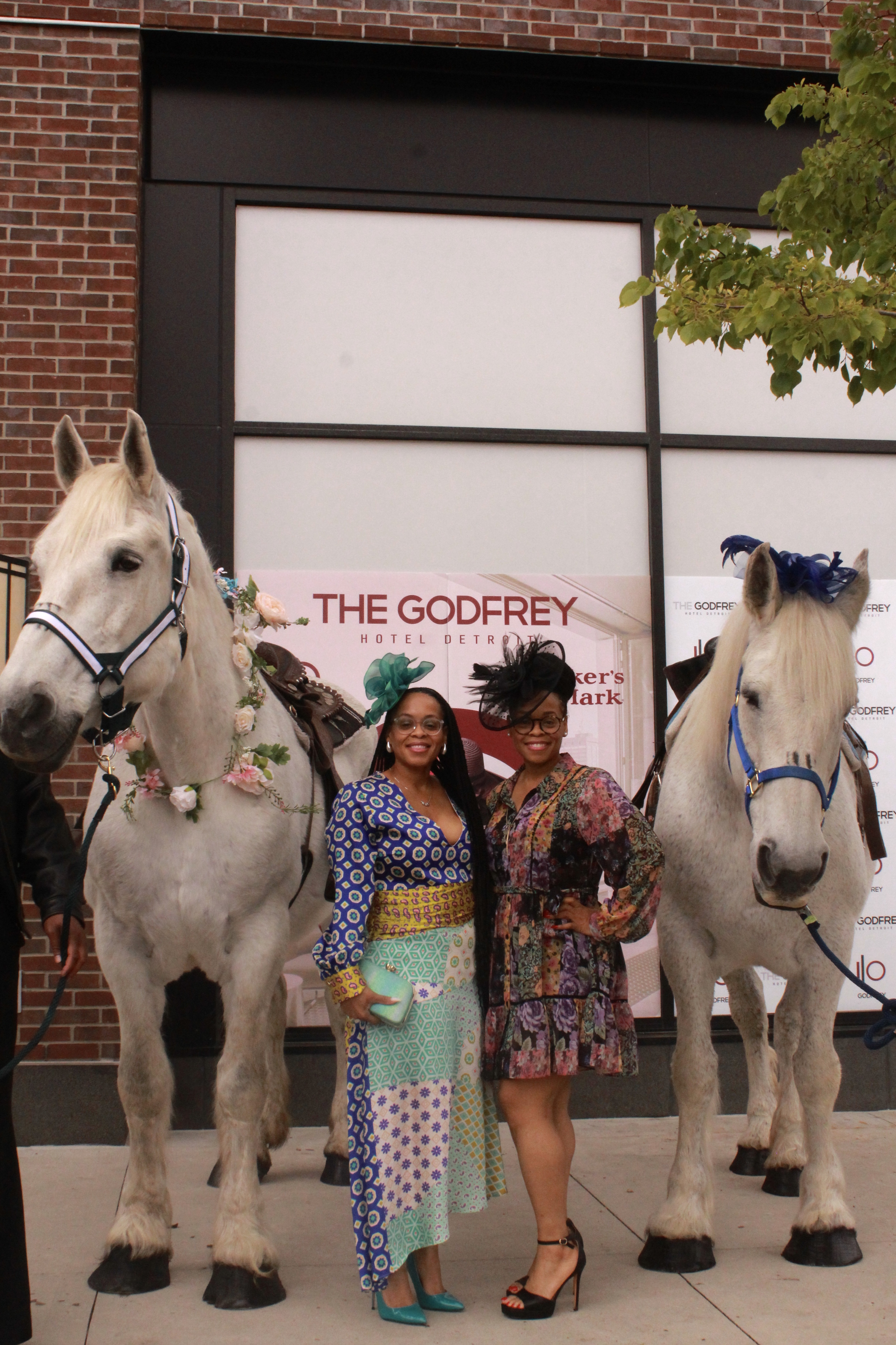  In front of the Godfrey Hotel Detroit, a set of identical, brown-skinned, female twins, pose in between a pair of identical, grey, female, Percheron (horse) sisters.