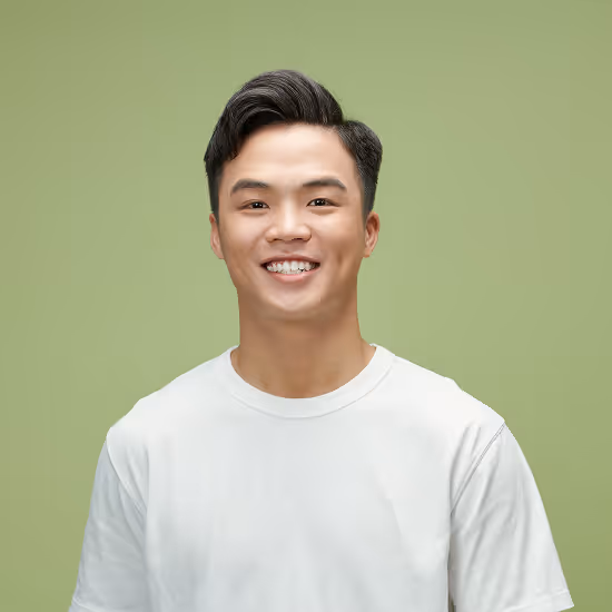 Smiling young Asian man with styled black hair wearing a white t-shirt against a light green background.