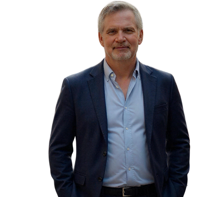Middle-aged man with gray hair and beard wearing a navy blazer over a light blue shirt.