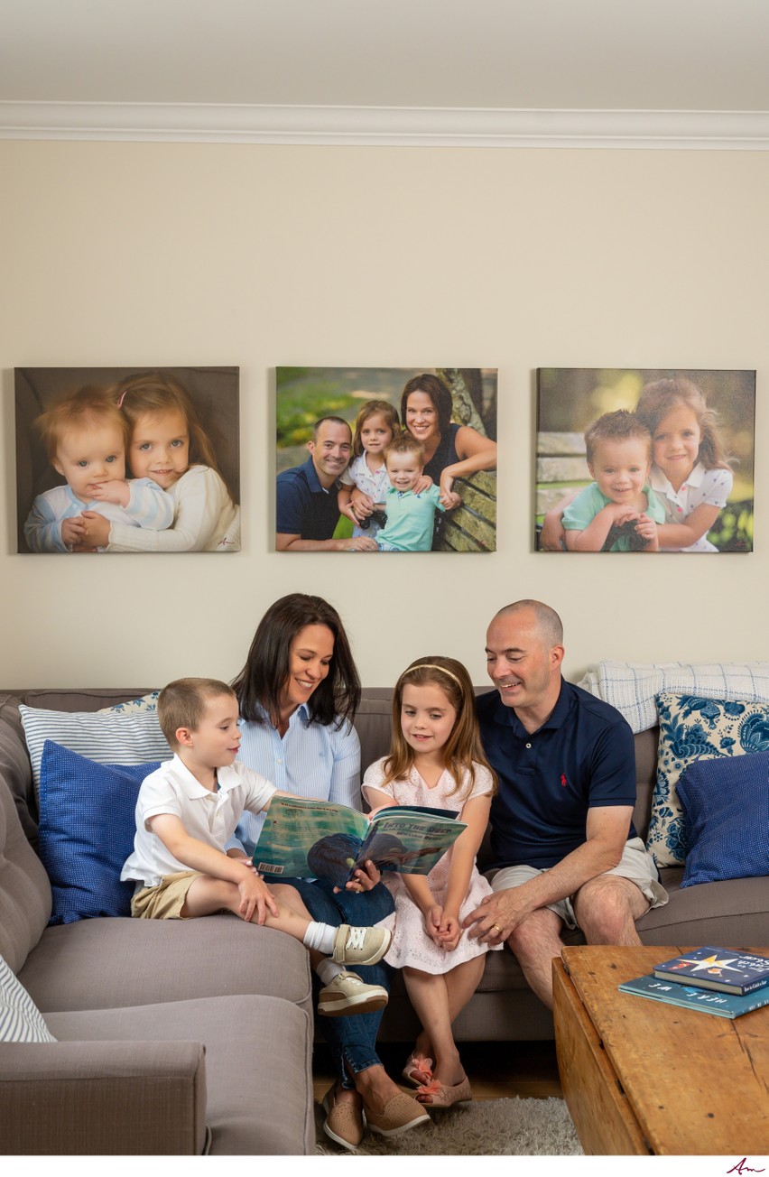 Bedford family reading on the couch beneath three canvas prints from their family session