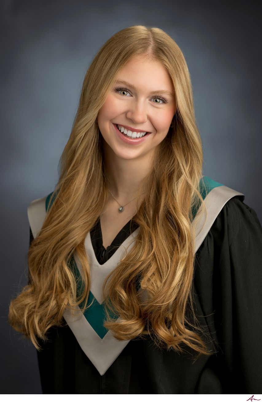 West Bedford High graduate in black gown with teal and silver V-sash, formal studio portrait