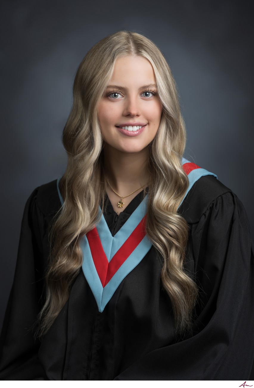 Bay View High senior in black gown with light blue V-sash and red chevron, studio grad portrait