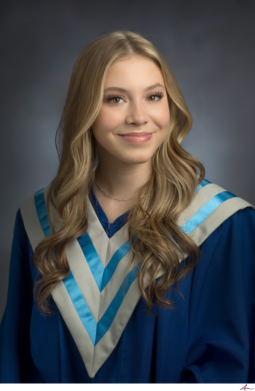 Lockview High senior in blue graduation gown with white and light blue V-sash, studio portrait
