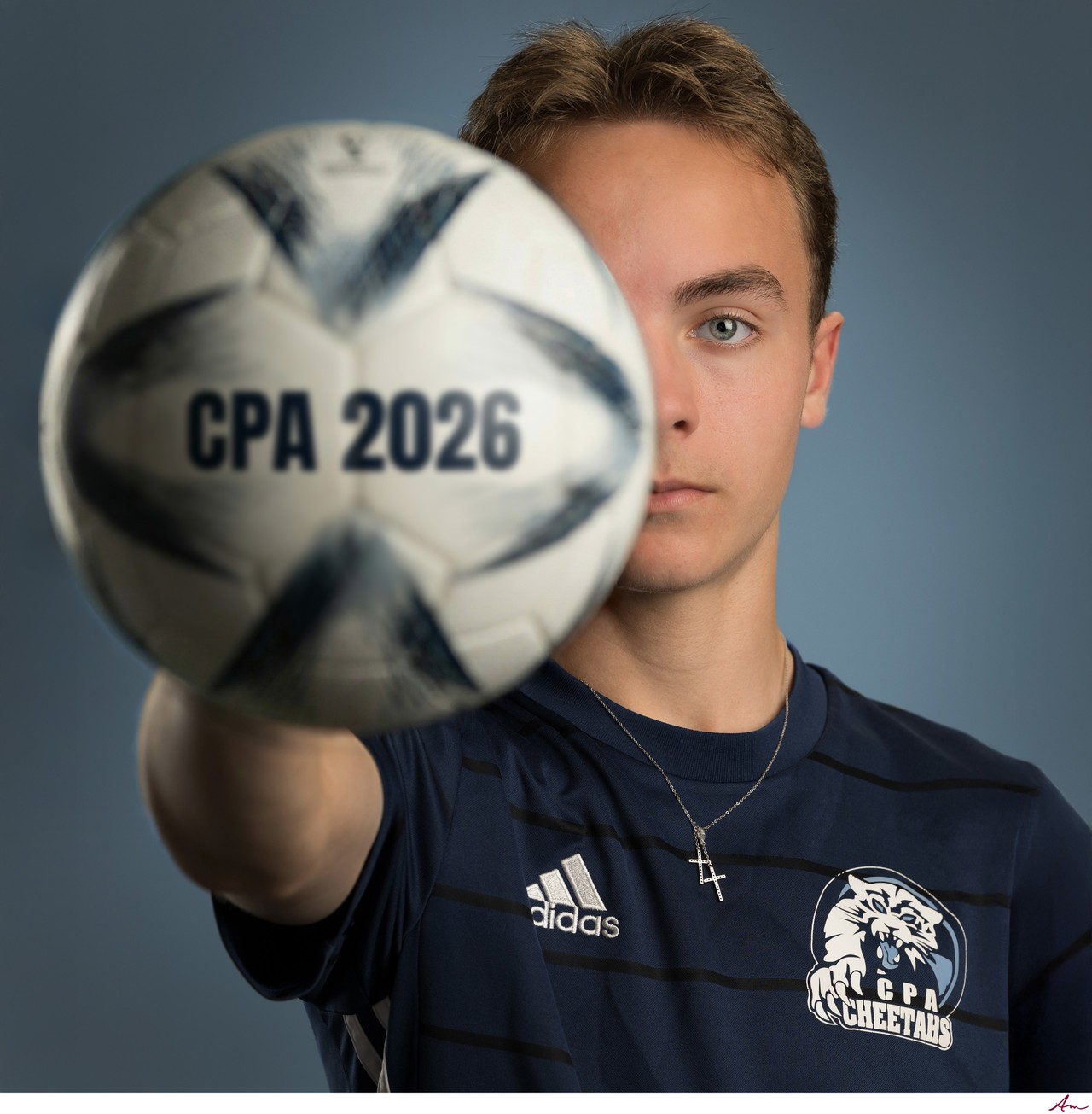 Charles P. Allen graduate in CPA Cheetahs jersey holding a soccer ball to the camera, Bedford