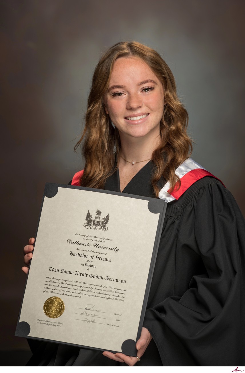 Dalhousie Bachelor of Science graduate holding her parchment in gown and Dal hood, Halifax