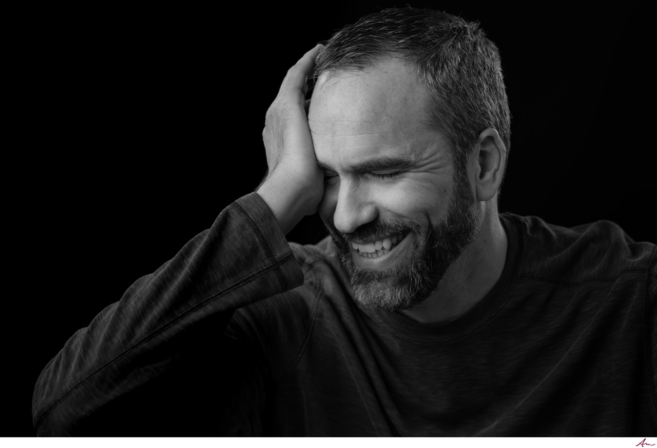 Black and white headshot of Halifax comedian Andrew Albert laughing with a hand over his face