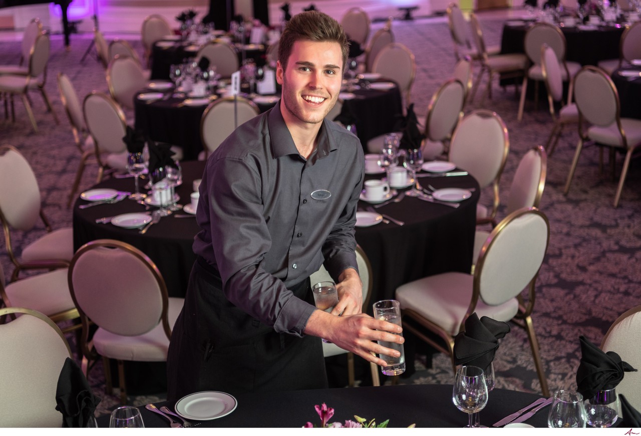 Server setting glasses in the Lord Nelson Hotel ballroom before a corporate dinner, Halifax