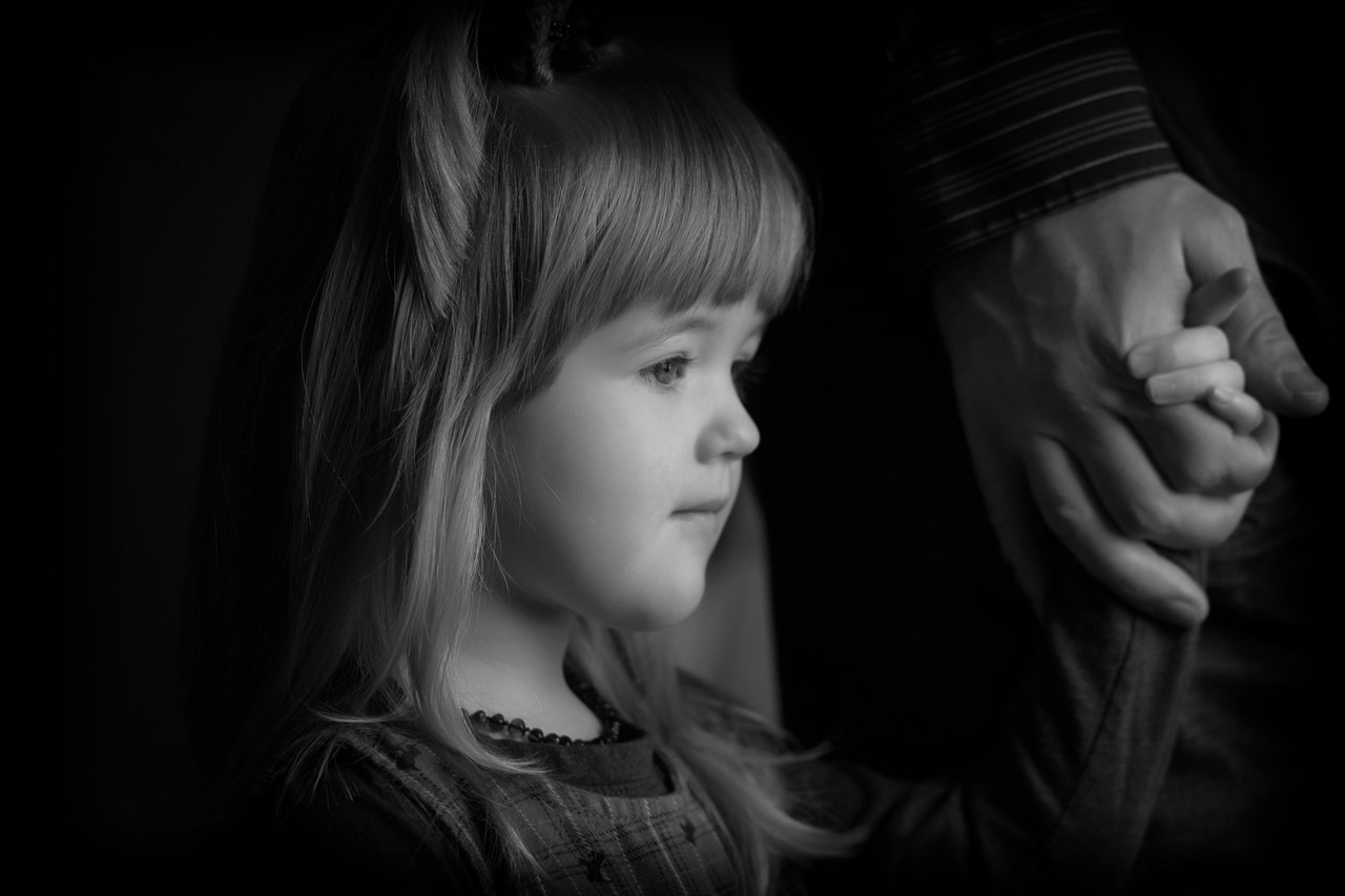 Black and white studio portrait of a young girl in profile holding her dad's hand, Halifax