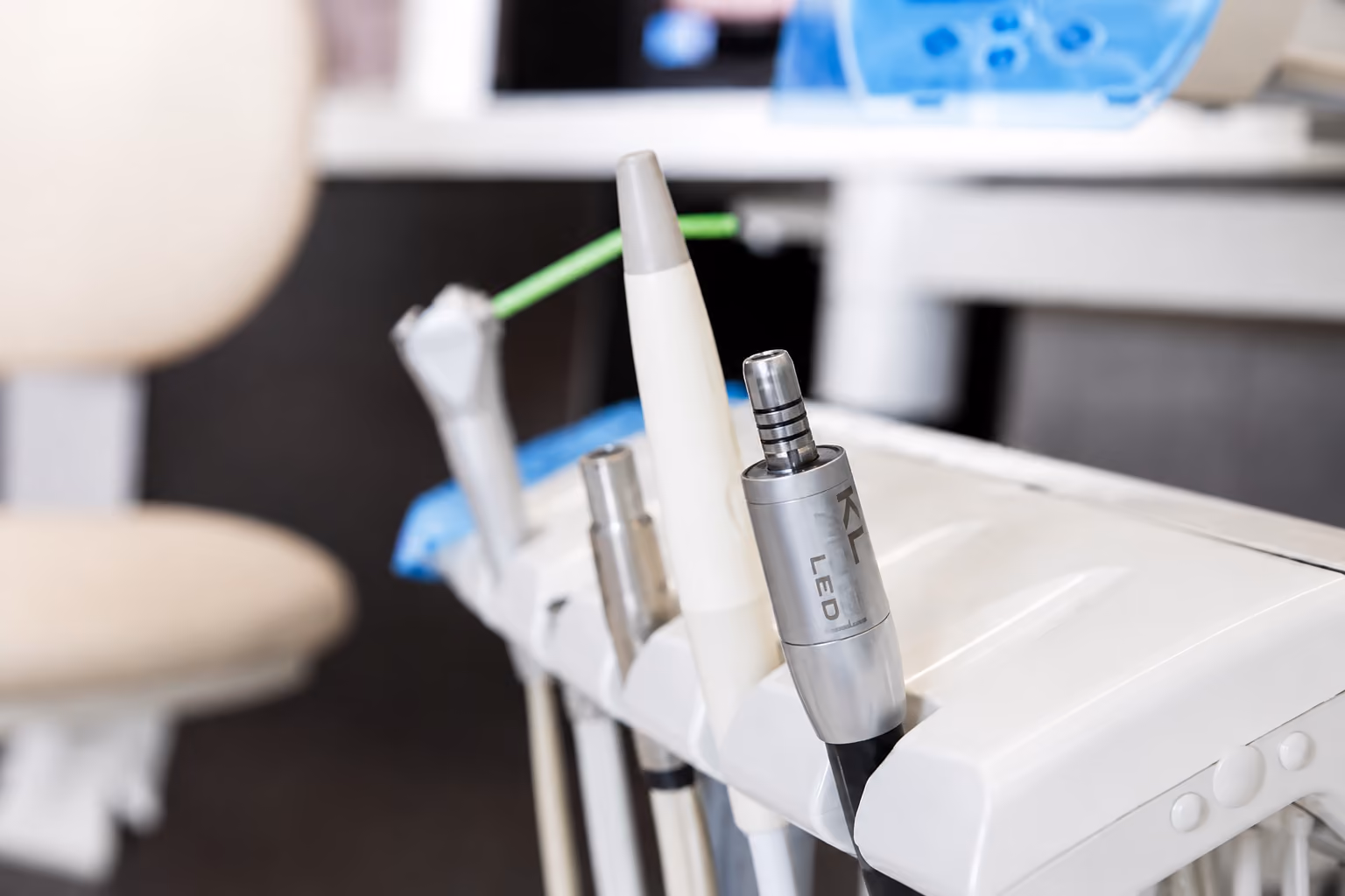 Close-up of dental tools including an LED handpiece on a white dental equipment tray.