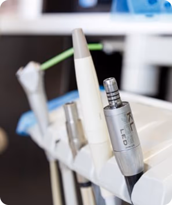 Close-up of dental tools including an LED handpiece on a white dental equipment tray.