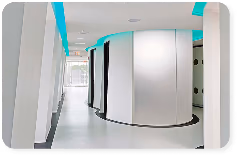 Modern, curved white hallway with black accents and blue ceiling lights in a clean interior space.