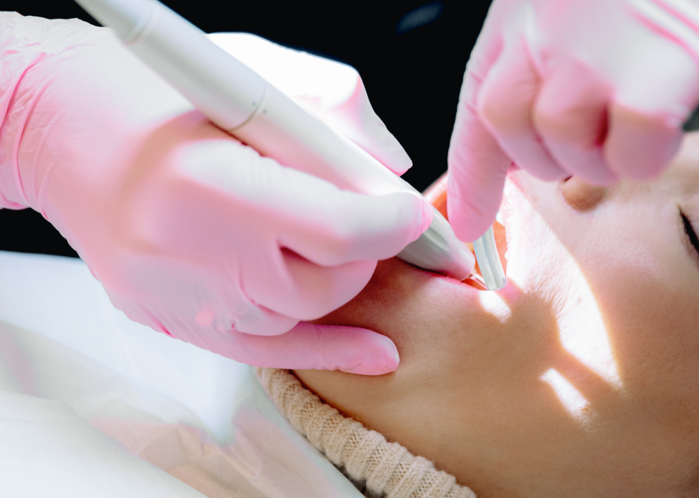 Dental professional wearing pink gloves performing a laser treatment inside a patient's mouth.