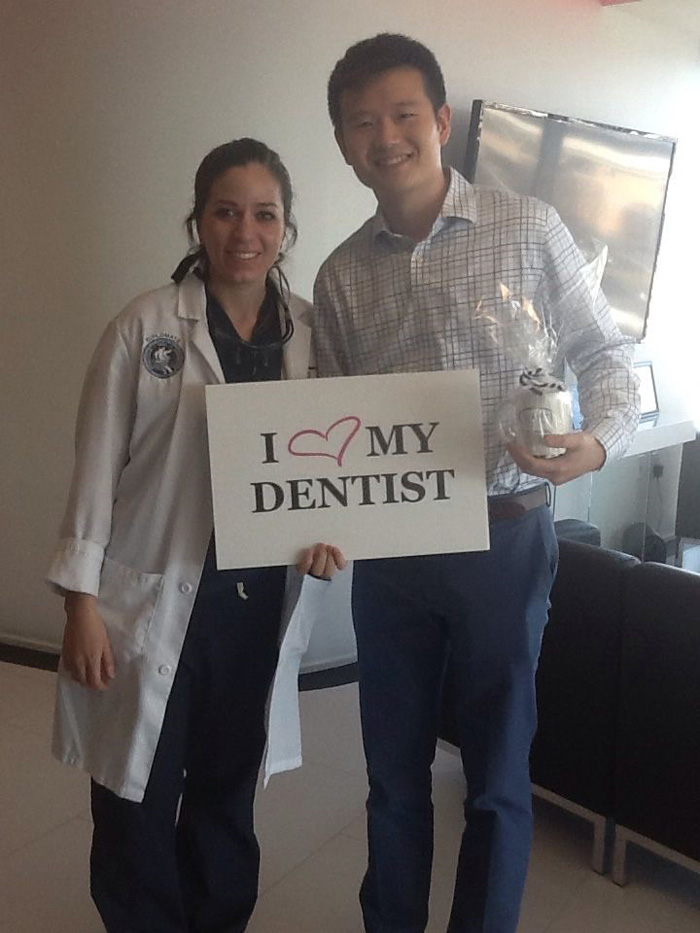 A man and a female dentist smiling, holding a sign that says 'I love my dentist.'