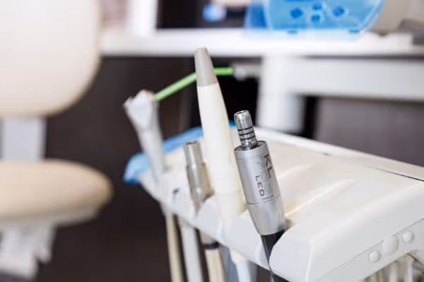 Close-up of dental tools including LED handpiece on a white dental unit in a clinic.