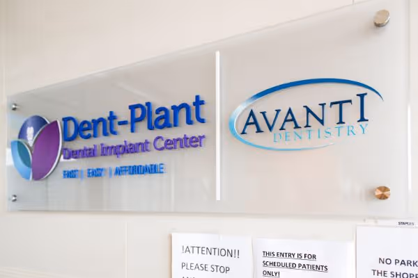 Wall sign with logos for Dent-Plant Dental Implant Center and Avanti Dentistry in blue and purple.