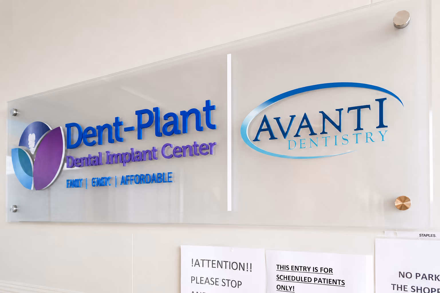 Wall sign with logos for Dent-Plant Dental Implant Center and Avanti Dentistry in blue and purple.