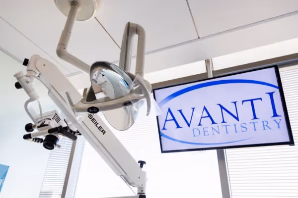 Dental clinic equipment including a light and a screen showing Avanti Dentistry logo.