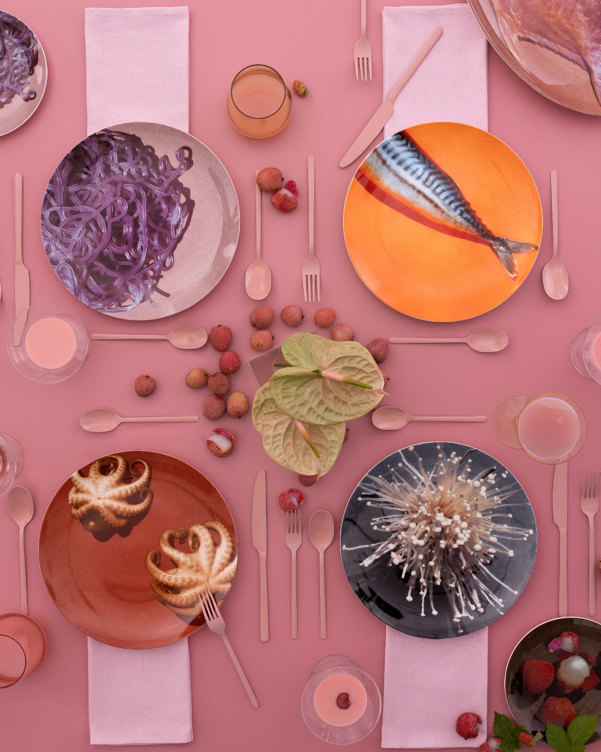 Pink-toned table styling with citrus, fish-form bowls, and sculptural ceramics